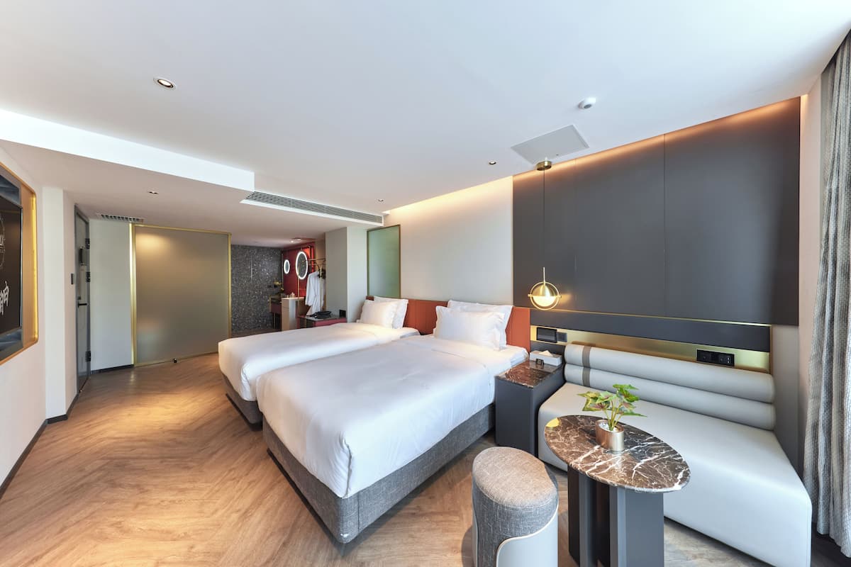 Une chambre d’hôtel moderne avec un grand lit, un coin salon et une petite table agrémentée d’une plante.