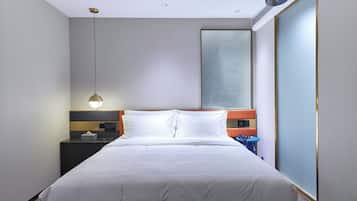 Una habitación de hotel moderna con una cama grande, una mesita de noche, un escritorio y un ventanal amplio.