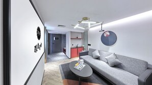 A modern living room with a grey sofa, a coffee table, and a kitchen in the background.