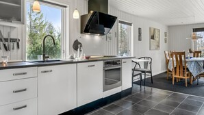 Et moderne køkken med hvide skabe, en stor ø og et spiseområde med træstole og et bord.