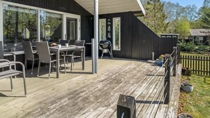 En moderne udendørs terrasse med spiseplads, grill og træterrasse.