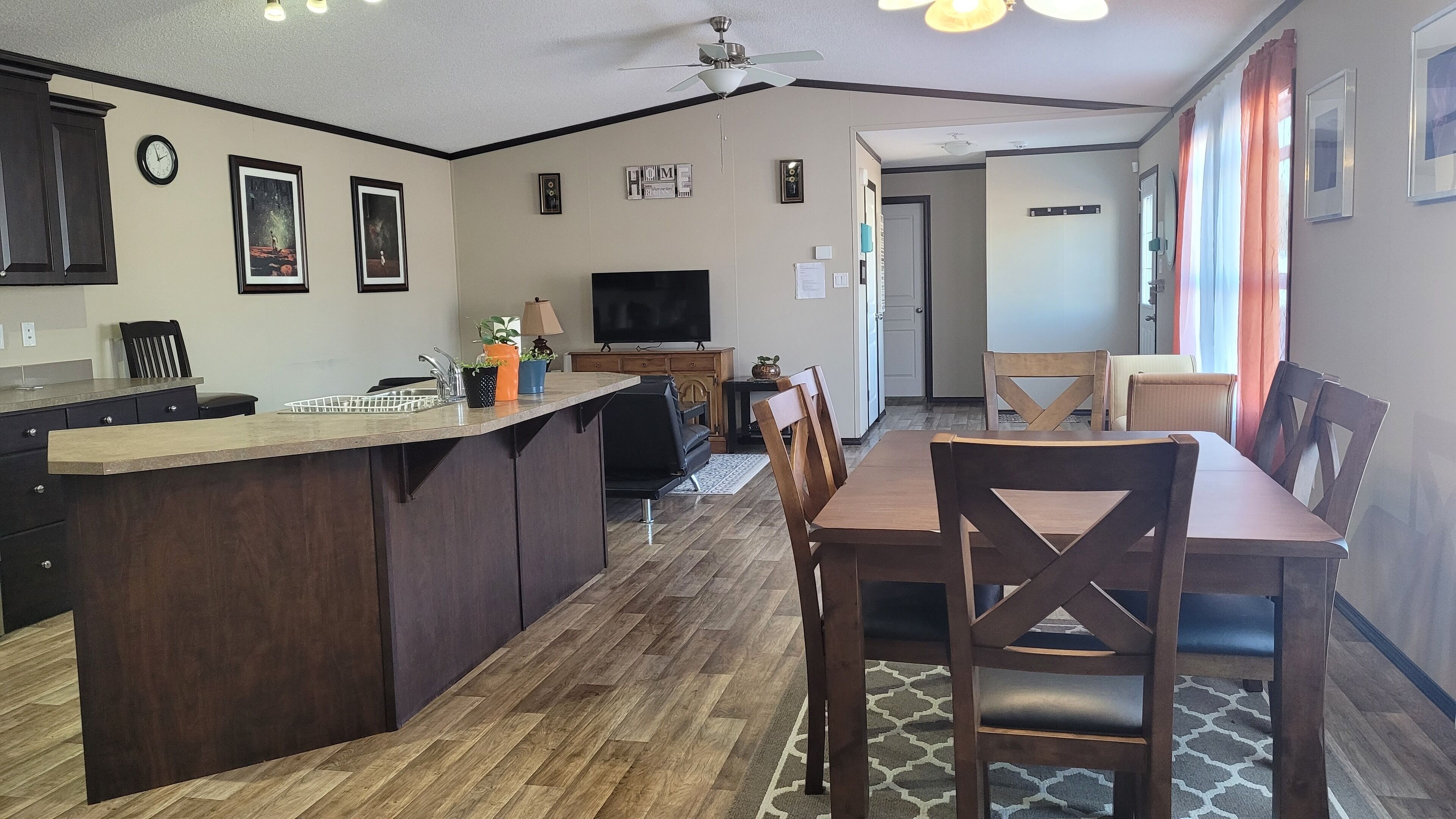 A modern kitchen with dark wood cabinets, a central island, and a dining area with wooden chairs.