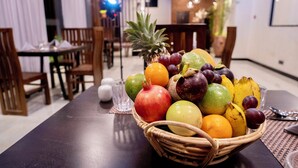 A dining area with a table set for two, featuring a fruit basket and a glass.