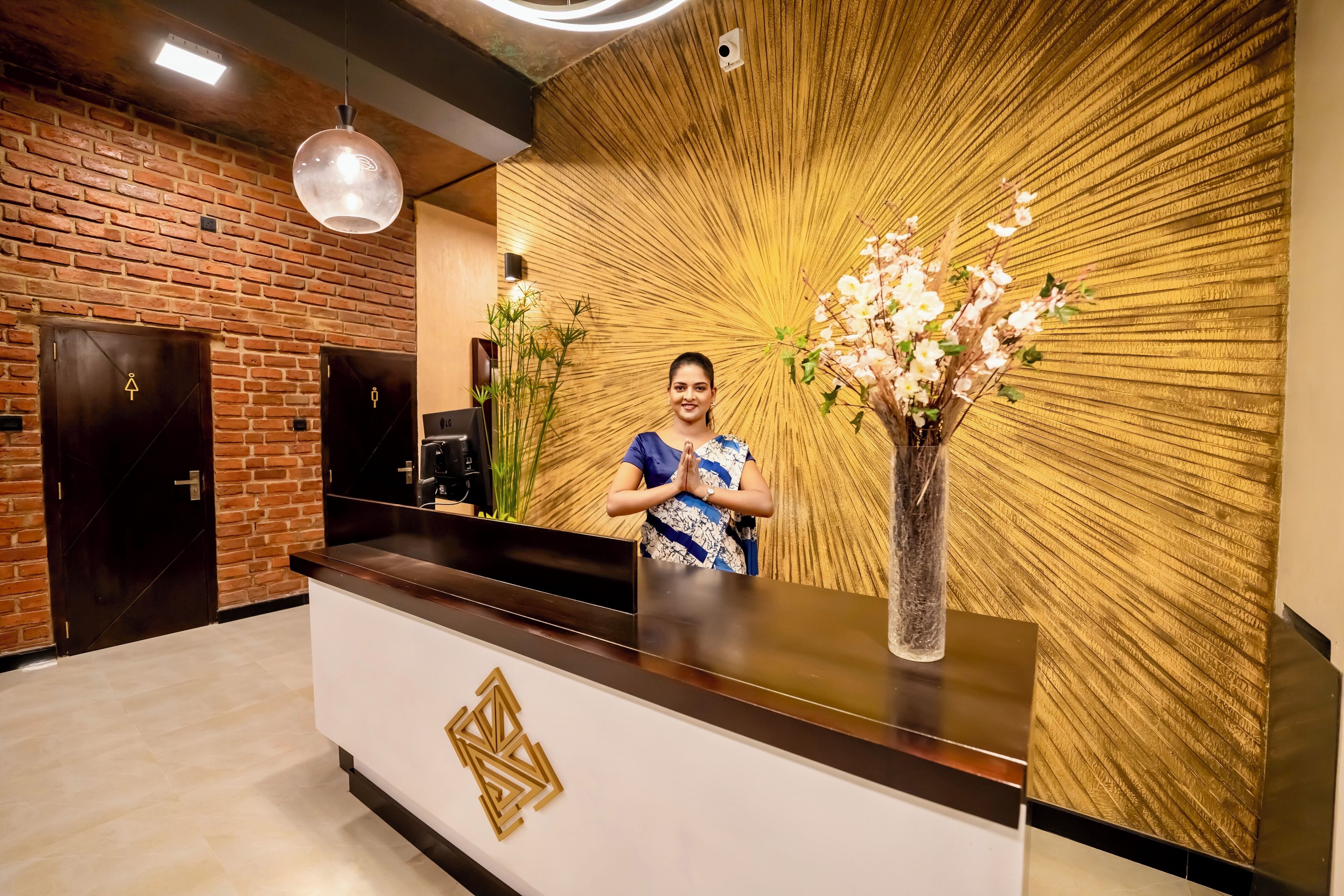 A reception desk with a modern design, a brick wall, and a decorative wall panel.