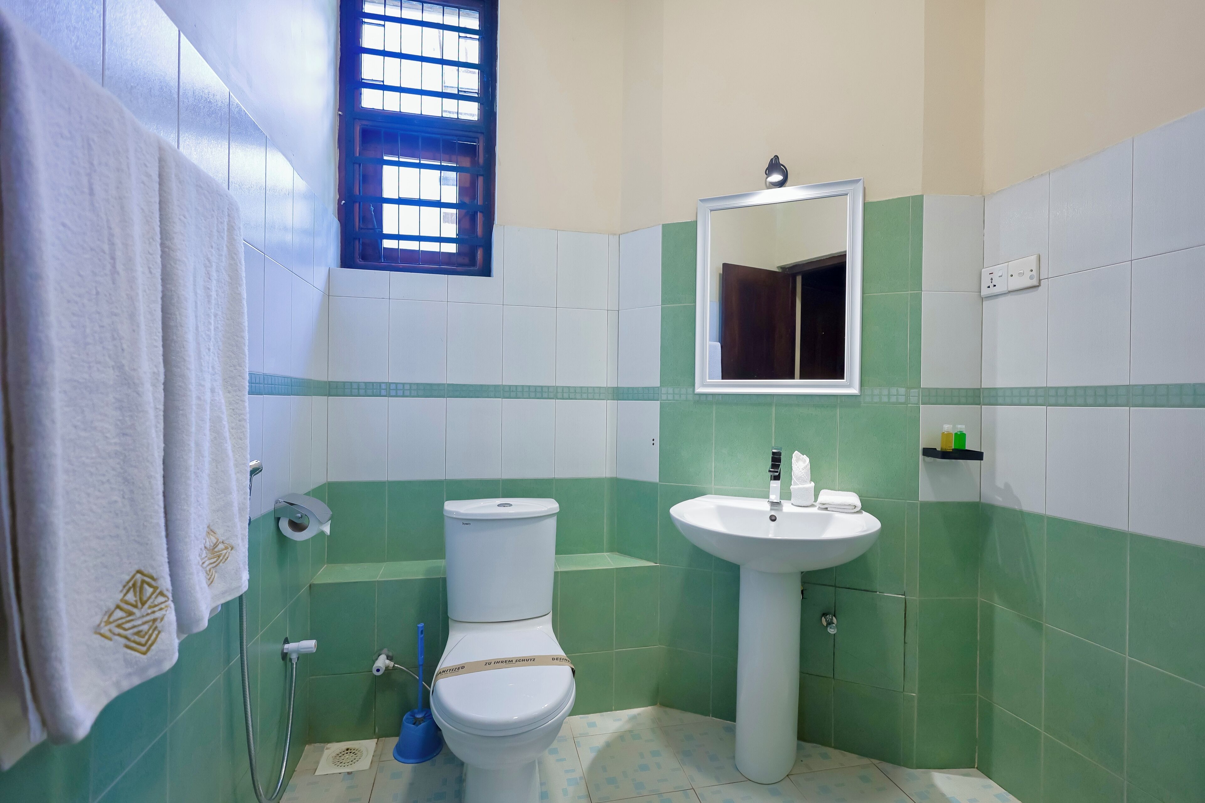 A bathroom with a toilet, sink, and window.