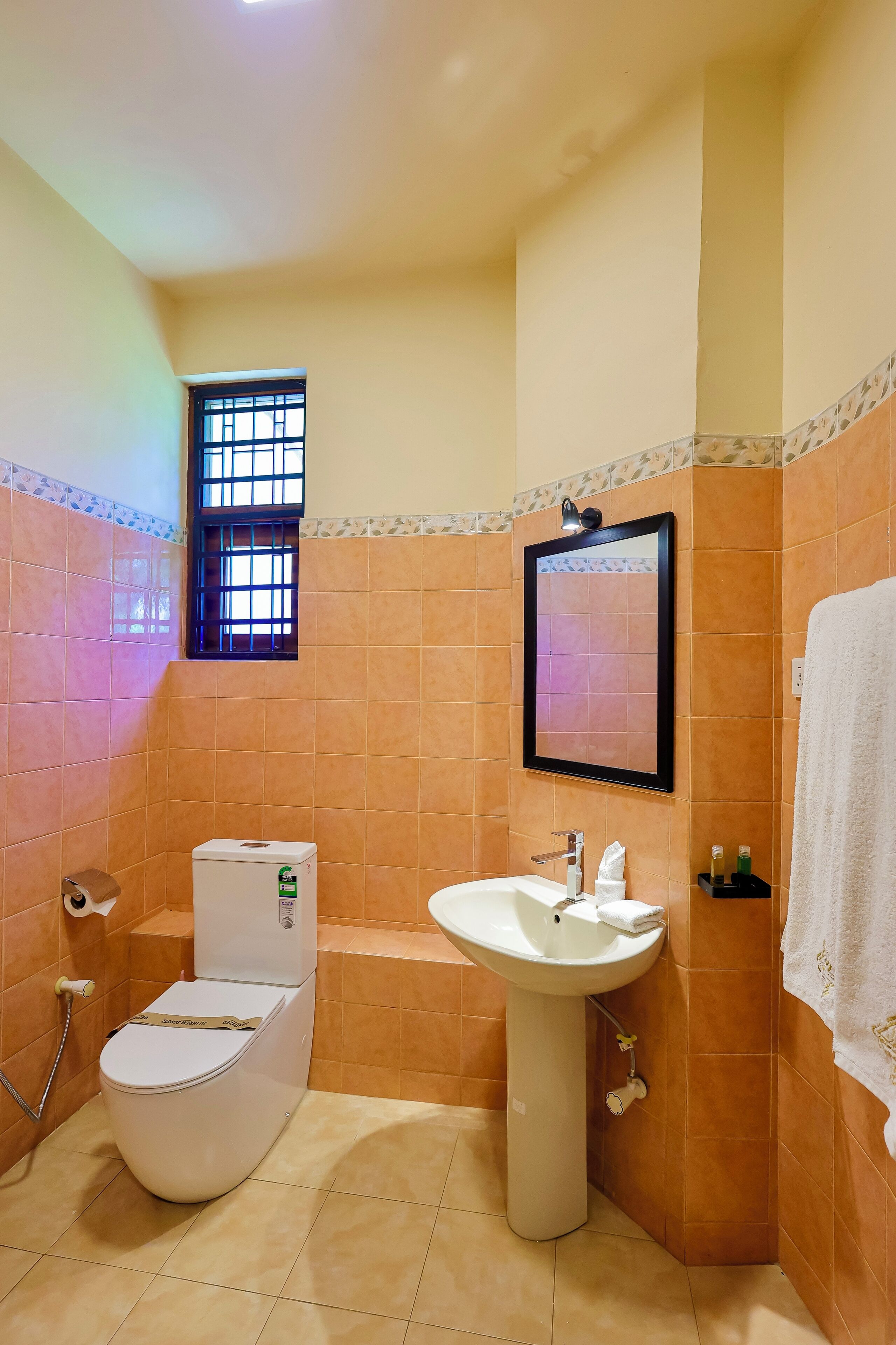 Une salle de bain avec des toilettes, un lavabo et une fenêtre.