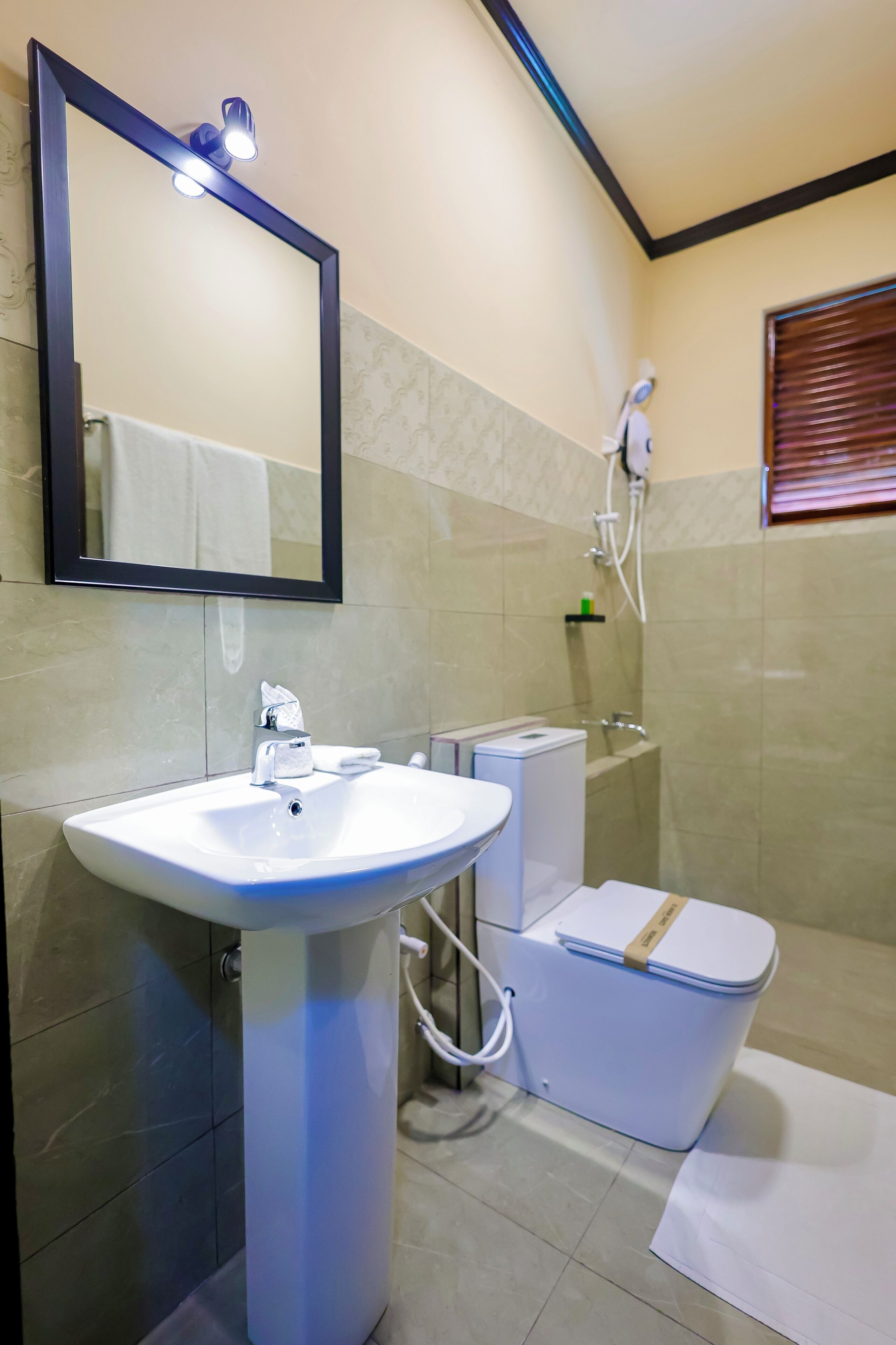 A bathroom with a sink, mirror, toilet, and shower.