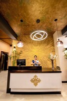 A reception desk with a modern design, featuring a geometric logo, a coffee machine, and a vase with flowers.