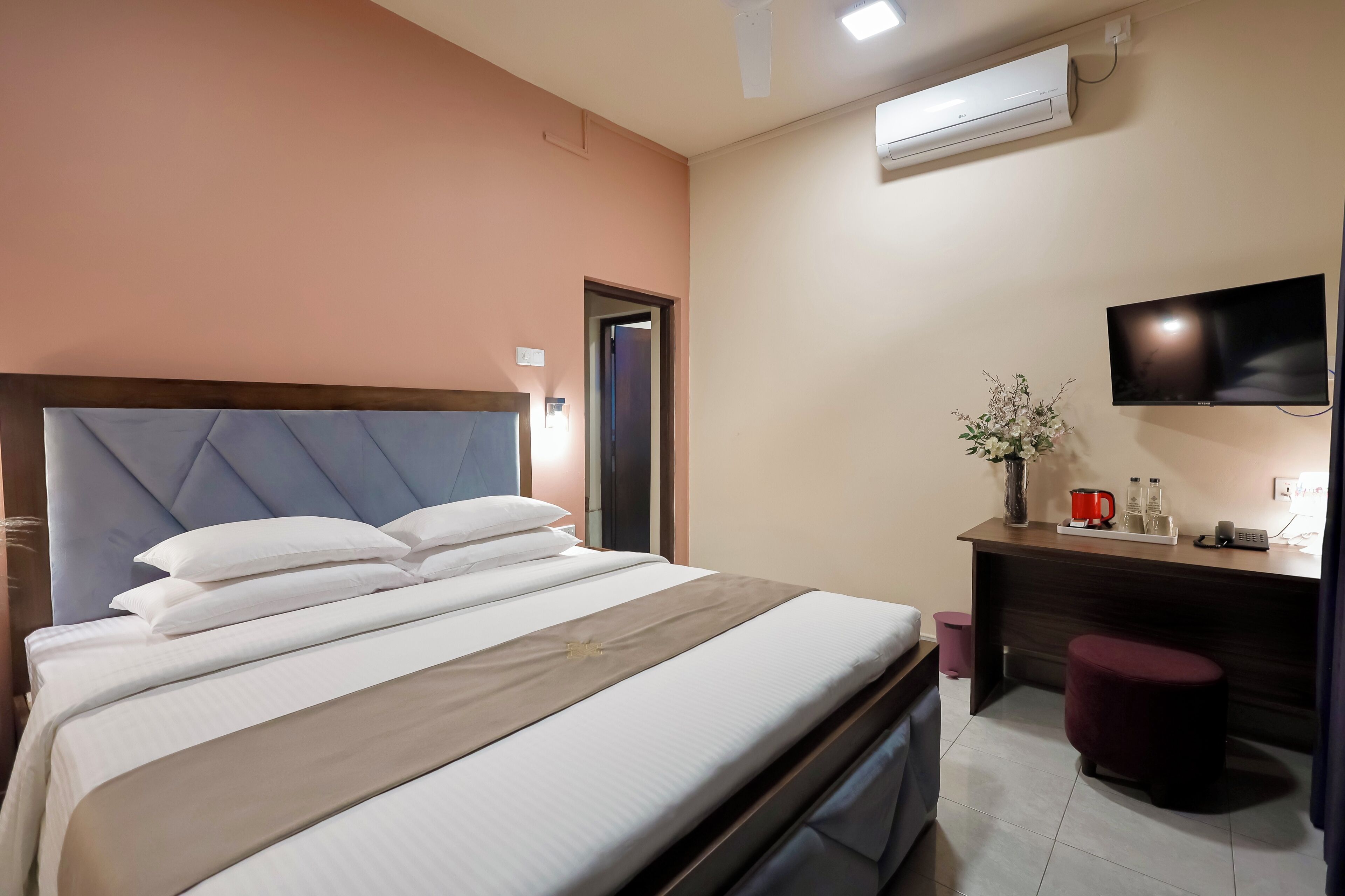 Ein Hotelzimmer mit Bett, Schreibtisch, Fernseher und Klimaanlage.
