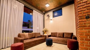 A modern living room with two brown sofas, a red ottoman, and a blue ottoman.