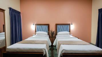 A hotel room with two beds, a mirror, and a nightstand with a vase.