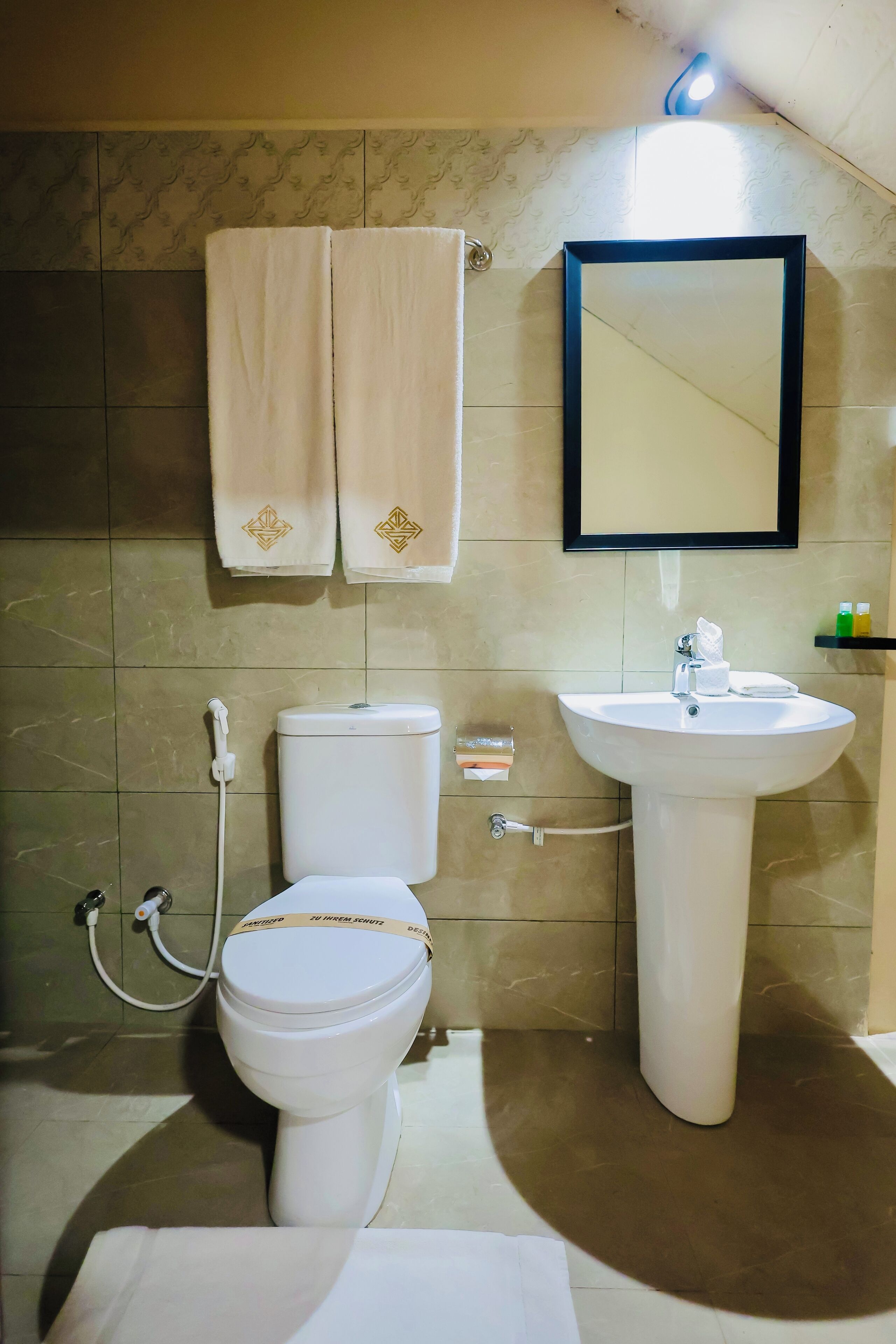 Un baño con inodoro, lavamanos y perchero para toallas.