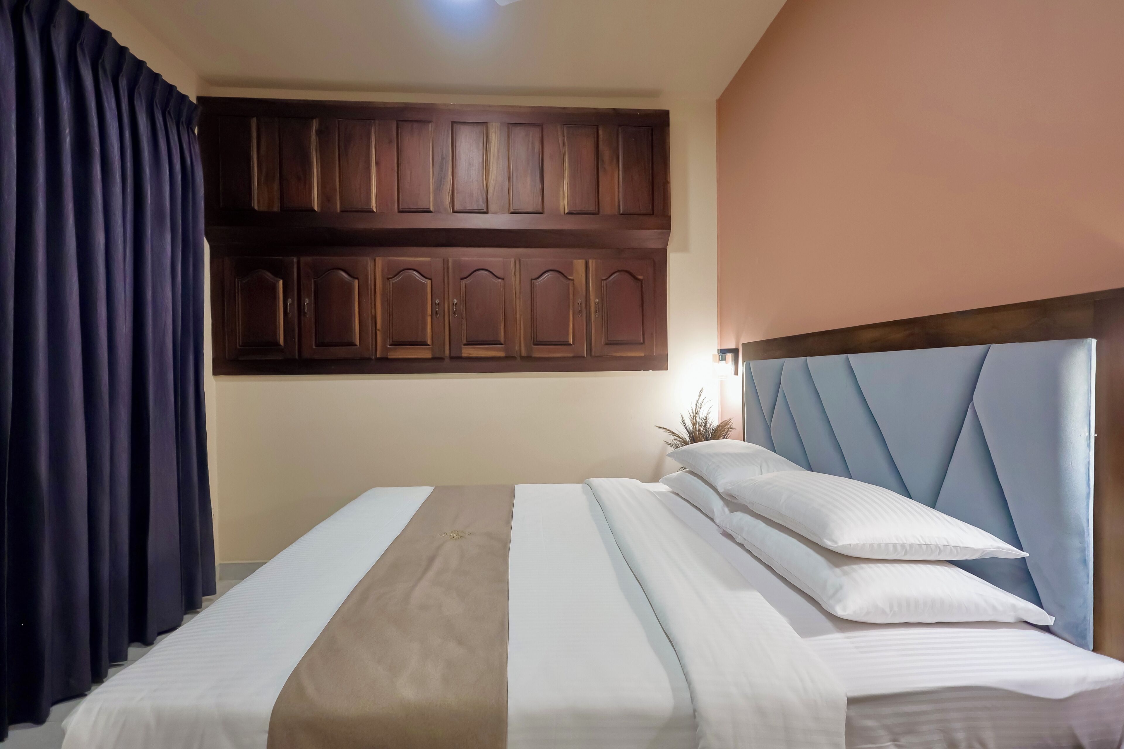 A hotel room with a bed, a headboard, and a wardrobe.