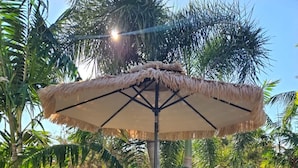 Eine Terrasse im Freien mit Lounge-Möbeln, einem Tisch und einem großen Sonnenschirm.