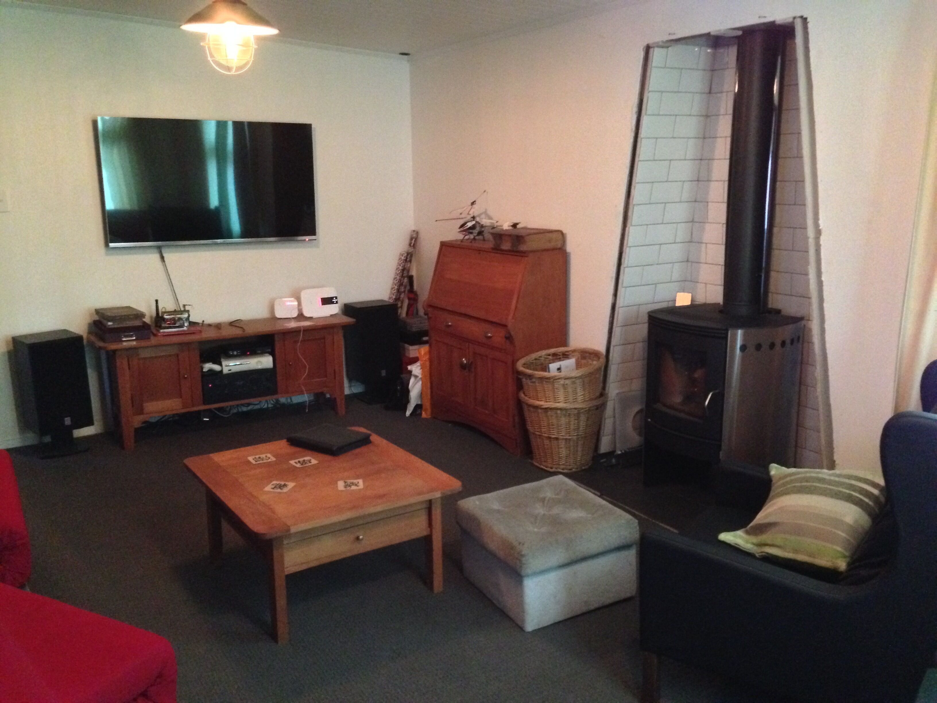 A living room with a flat-screen TV, wooden furniture, a fireplace, and a TV stand.