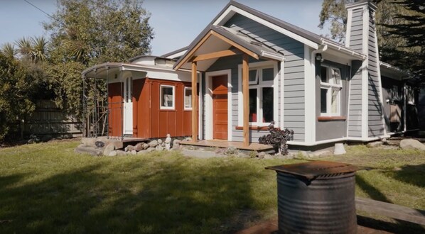 Ein zweistöckiges Haus mit Veranda, Garage und einem kleinen Garten.