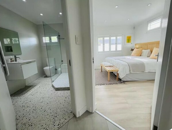 A modern bedroom with a bed, bedside table, and a view of the bathroom.