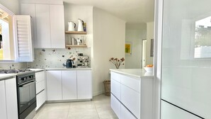 A modern kitchen with white cabinetry, a built-in oven, and a coffee machine. - Dune • has a pool • 600m to Beach Robberg 5 (Plettenberg Bay)