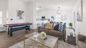 A modern living room with a pool table, a sofa with decorative pillows, and a coffee table. - Spacious Yard+Pool Table at 5BR Modern Getaway (North Las Vegas)