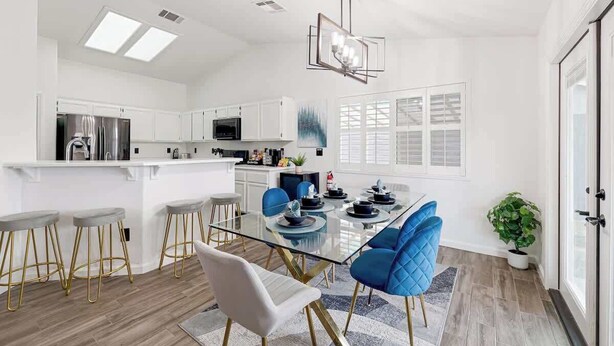 A modern kitchen with white cabinets, a central island, and bar stools. - Spacious Yard+Pool Table at 5BR Modern Getaway (North Las Vegas)