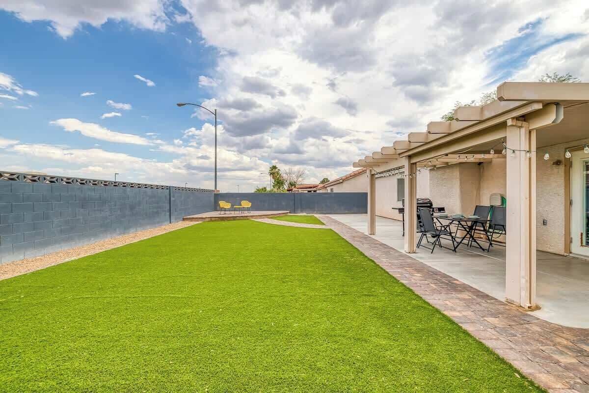Un'area patio con prato verde, mobili da esterno e una zona coperta con tavolo e sedie.