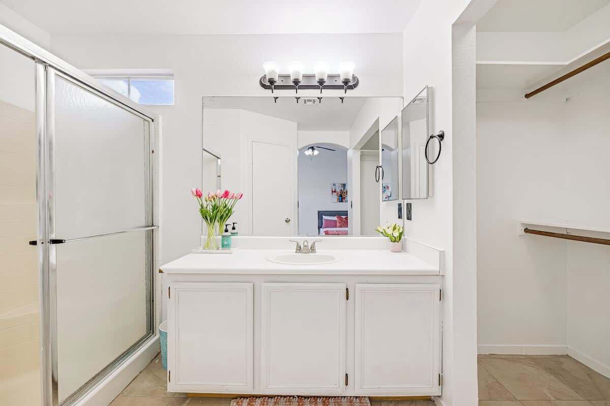 A modern bathroom with a white vanity, a large mirror, and a glass shower enclosure.