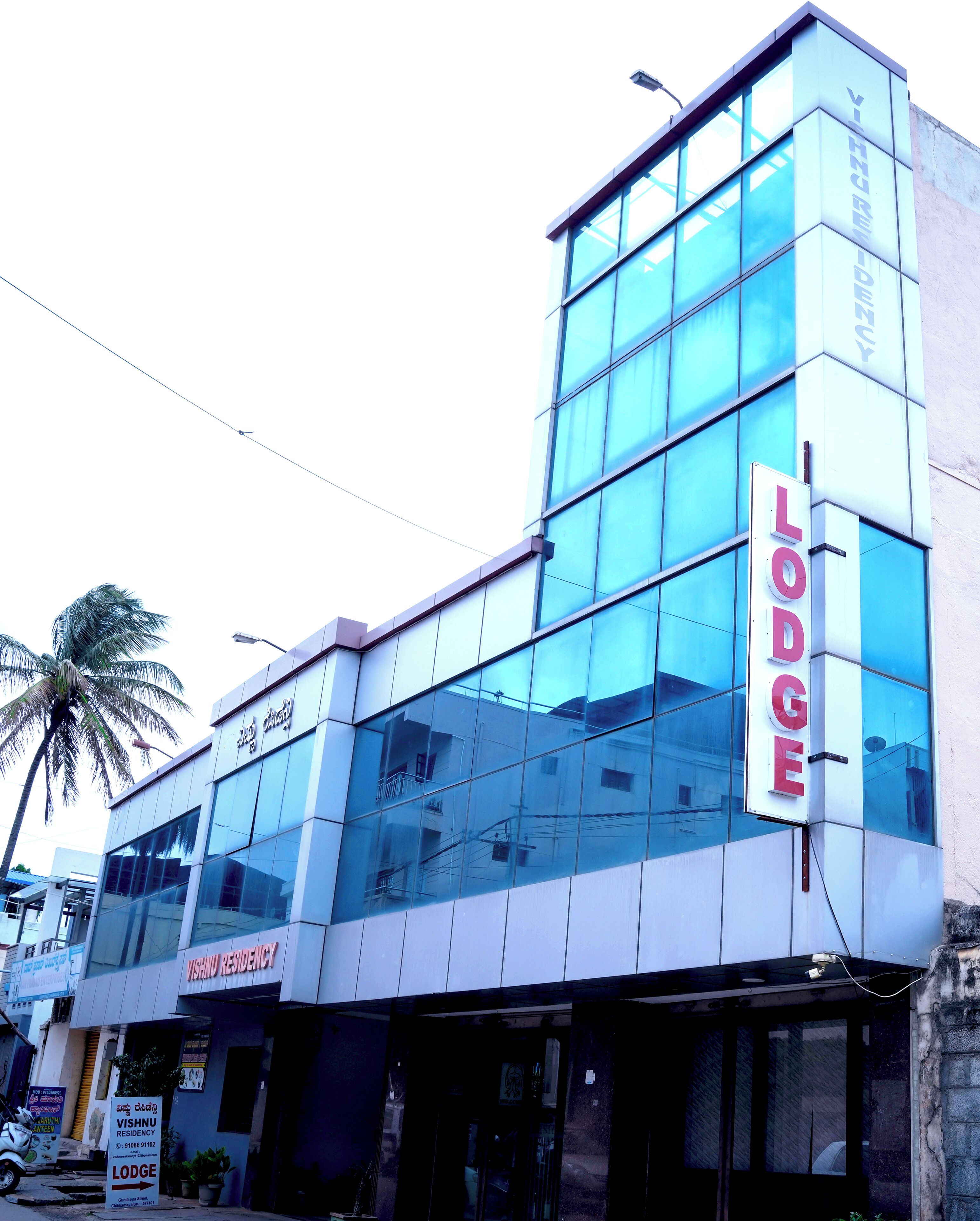 A modern building with a sign reading "Lodge Vishnu Residency."