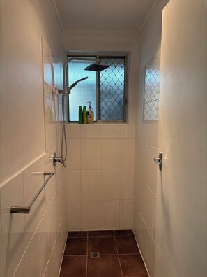 A small, tiled shower room with a window, a handrail, and a showerhead. - Sunflower Homes Classy and Cozy (Para Hills)