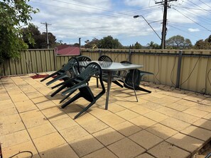 An outdoor patio with a table and chairs, a tiled floor, and a fence. - Sunflower Homes Classy and Cozy (Para Hills)