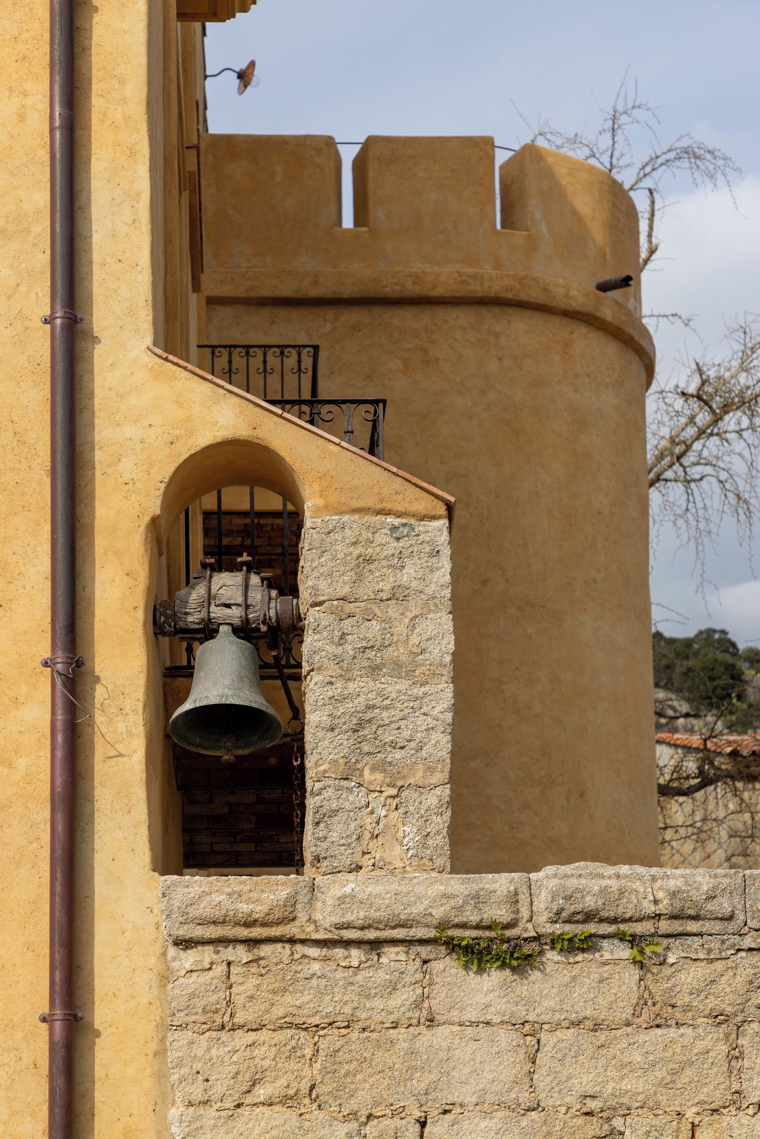 A bell tower with a stone bell housed in a brick archway.