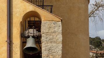 A bell tower with a stone bell housed in a brick archway.