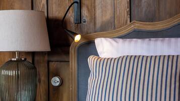 A wooden headboard with a lamp and a striped pillow on a bed.