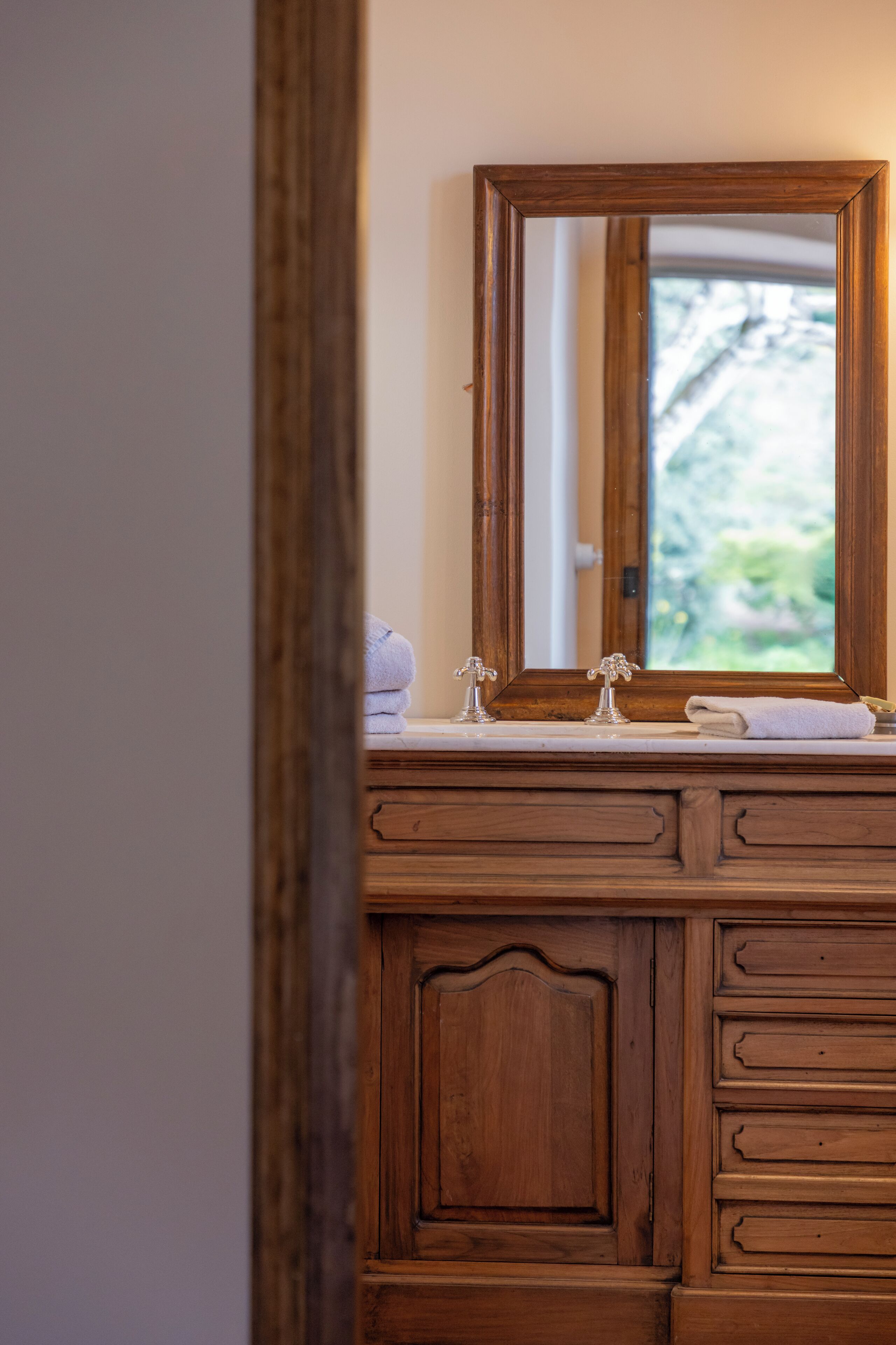 Une coiffeuse en bois avec un miroir, un lavabo et une serviette.