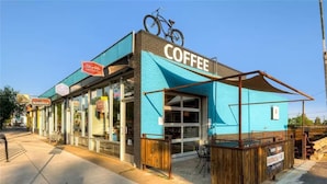 Kahvila, jossa on sininen markiisi, polkupyörä katolla ja kyltti, jossa lukee: ”Sloth Coffee Co.”