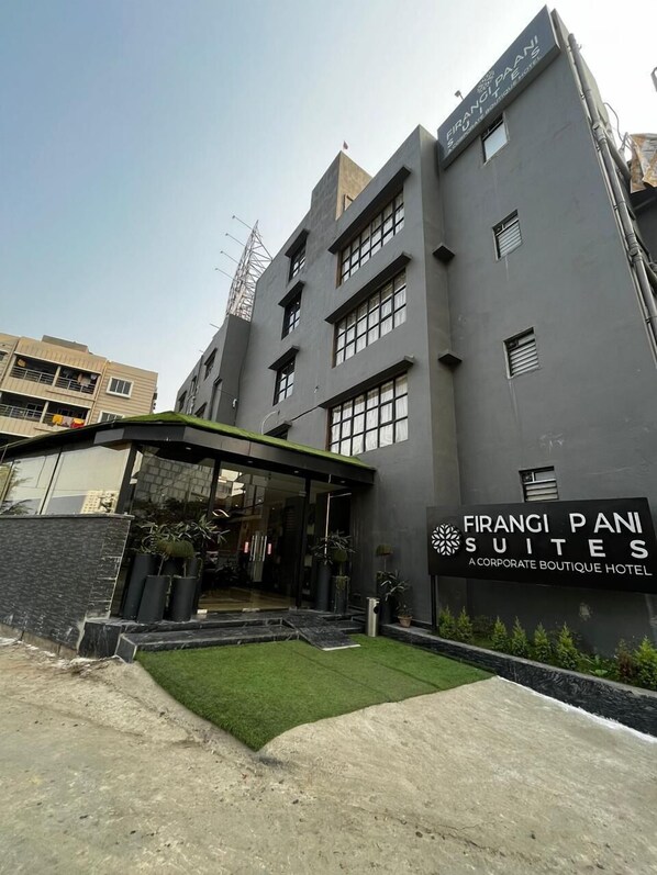 A modern building with a sign for 'Firangi Pani Suites' indicating it is a corporate boutique hotel.