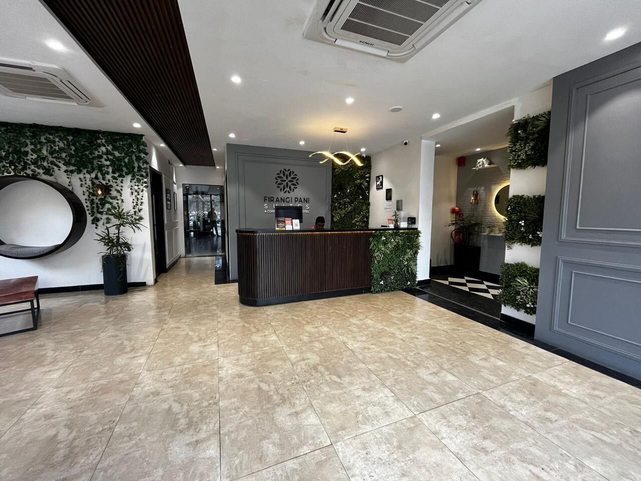 A reception area with a wooden reception desk, a large circular wall decoration, and a checkered floor pattern.