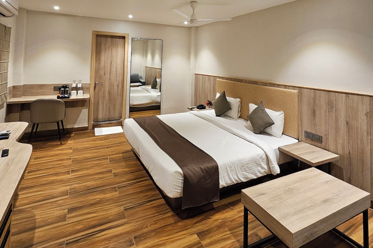 A modern hotel room with a large bed, bedside tables, a desk, and a mirror.