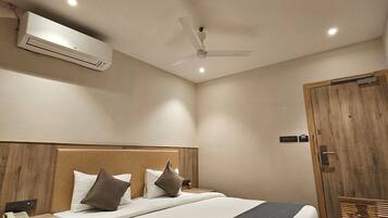 Quarto de hotel com cama, mesa de cabeceira, criado-mudo e guarda-roupa.