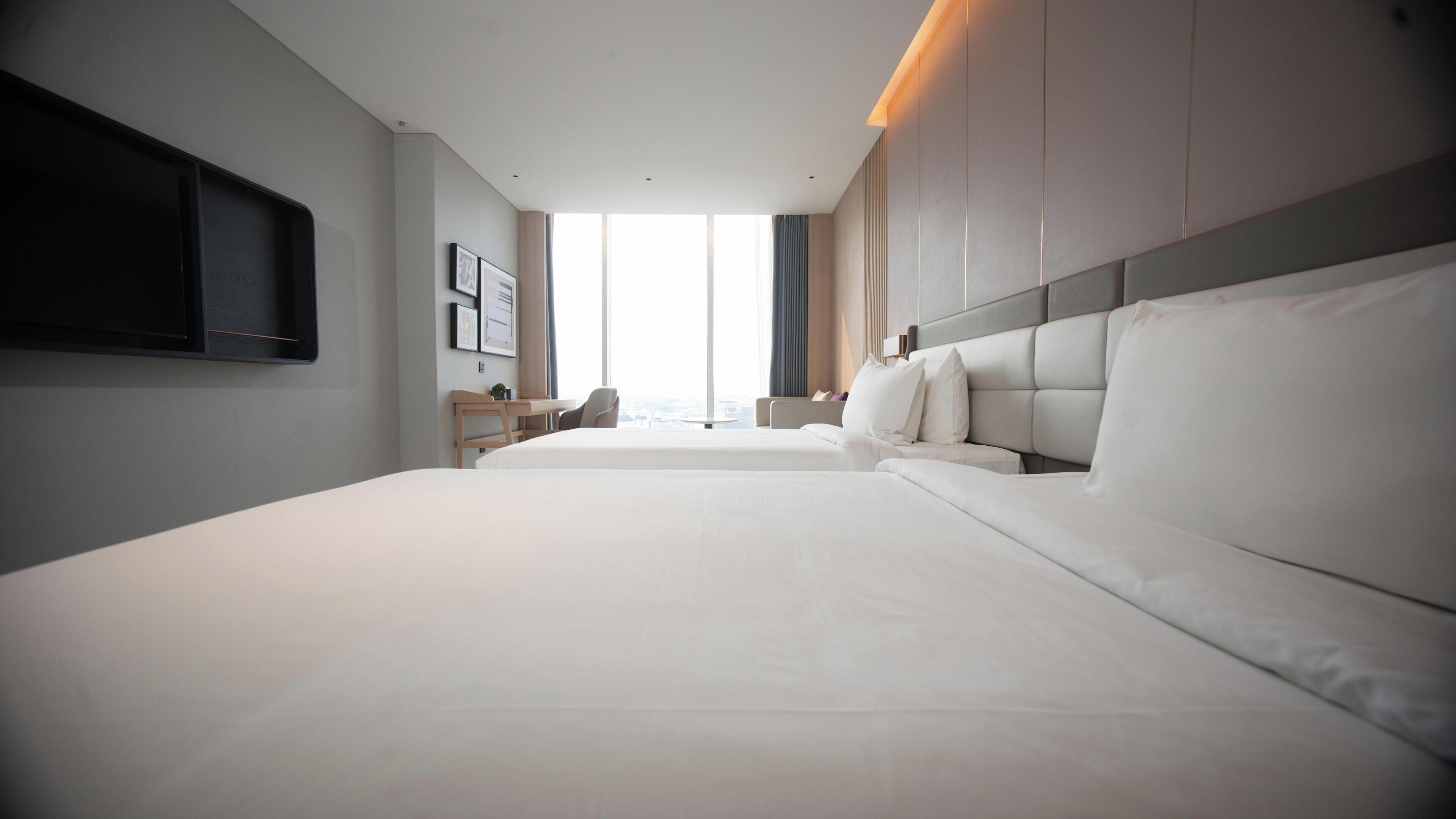 Habitación de hotel con una cama grande, un escritorio y una televisión en la pared.