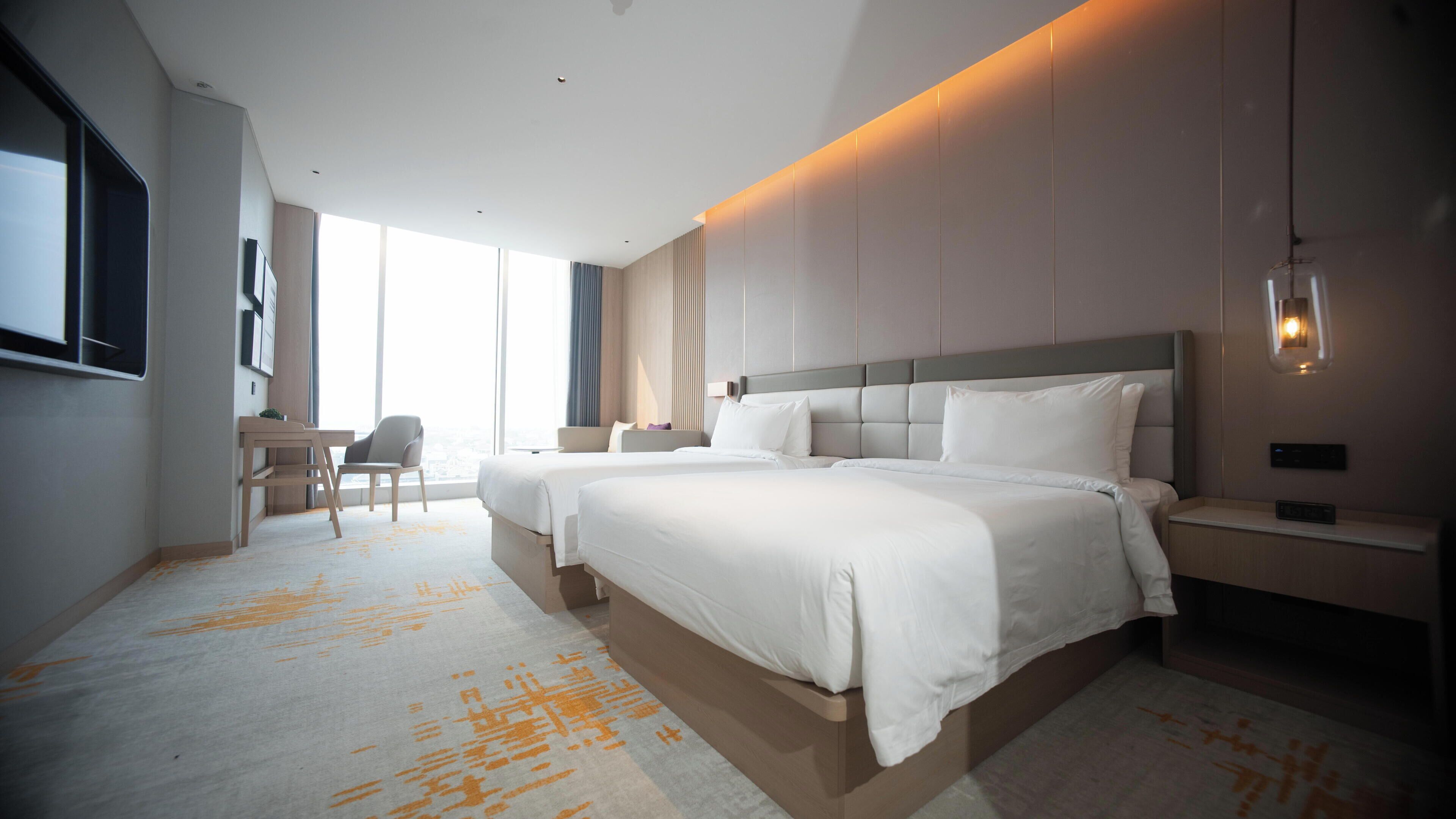 Ein modernes Hotelzimmer mit einem großen Bett, Nachttischen, einem Schreibtisch und einem Sessel.