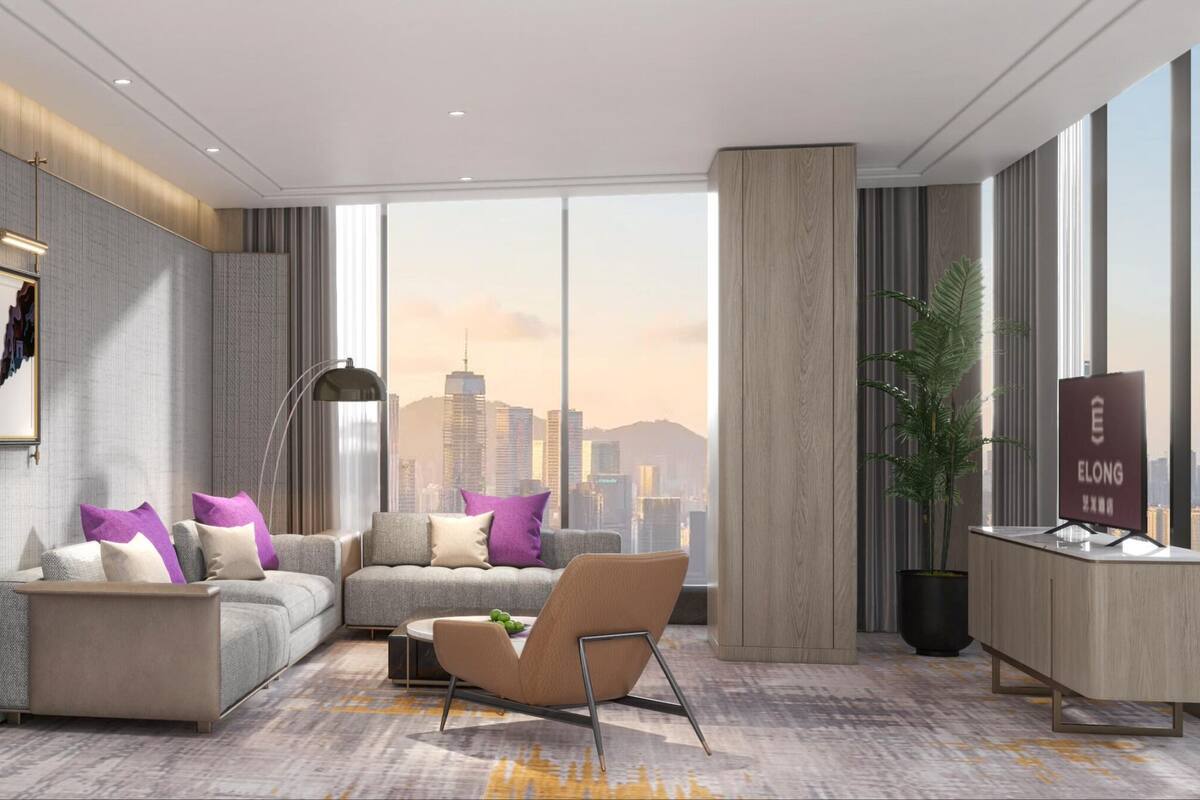 Quarto de hotel moderno com cama, sofá, poltrona e escrivaninha, com vista para a paisagem urbana.