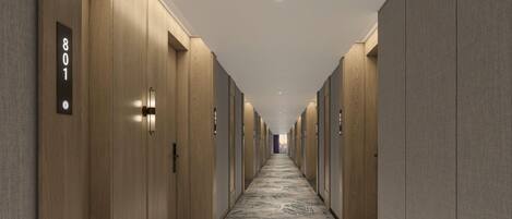 A long, narrow hallway with wooden walls and numbered doors, leading to individual rooms.