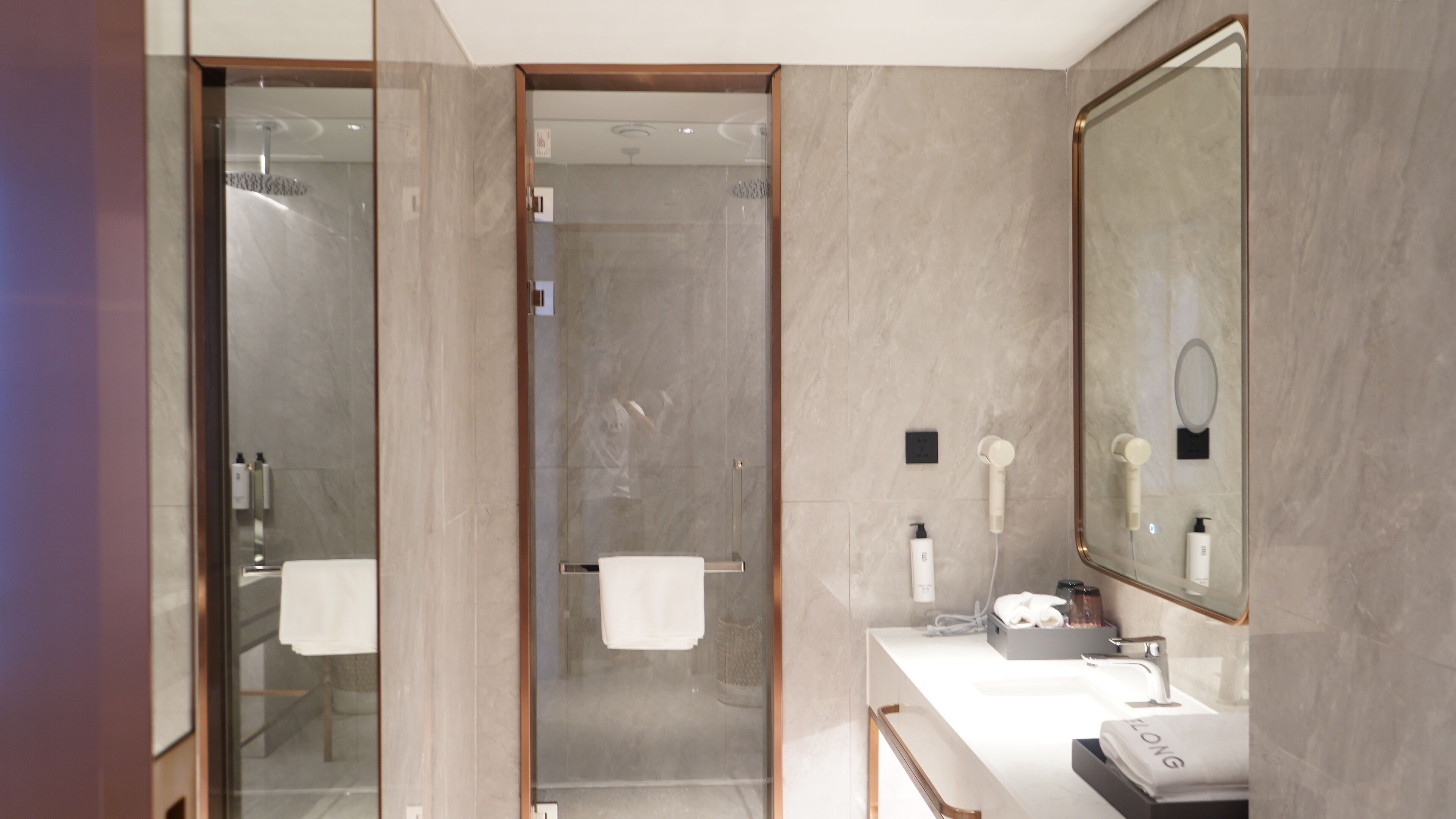 A modern bathroom with a glass shower enclosure, a large mirror, and a vanity with a sink and towel rack.