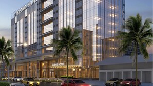 A modern hotel with a glass facade, multiple floors, and a prominent entrance. - Elong Hotel Jakarta PIK (Jakarta)