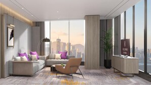 A modern hotel room with a large city view, a sofa set, a desk, and a potted plant. - Elong Hotel Jakarta PIK (Jakarta)