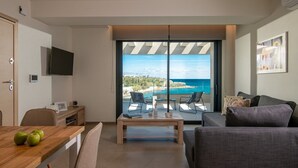 Uma sala de estar moderna com uma grande porta de vidro deslizante que dá para uma varanda com vista para o mar.