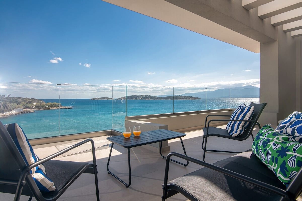 Un balcon avec une table et des chaises, offrant une vue sur la côte.