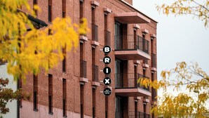 Un immeuble à plusieurs étages, reconnaissable à son grand panneau « BRIX », qui présente une architecture moderne avec des éléments en briques et de grandes fenêtres.