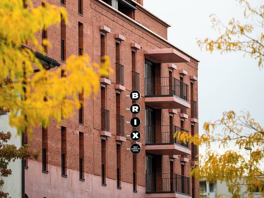 Un edificio de varios pisos con un llamativo letrero 'BRIX', que presenta un diseño arquitectónico moderno con detalles de ladrillo y amplias ventanas.