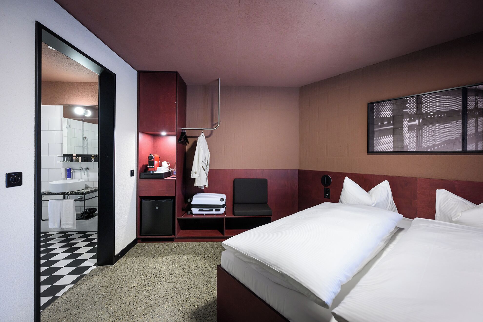 Habitación de hotel con cama, escritorio, silla, mesita con cafetera y espejo.